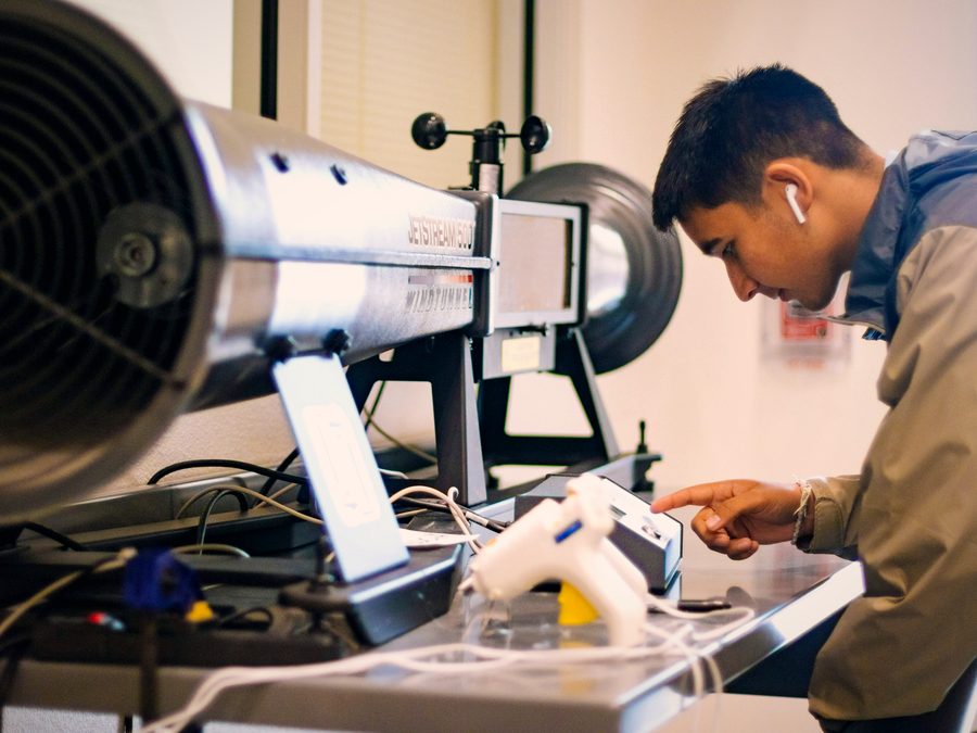 A student testing a design in a classroom wind tunnel.